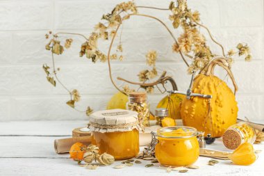 Antika eczacılık tarzında sağlıklı gıda konsepti. Ev yapımı kabak püresi ve beyaz ahşap bir masada cam kavanozlarda humus. Balkabağı, kurutulmuş zıpzıp ve bitki özü ile kırsal sonbahar natürmortu, kopyalama alanı