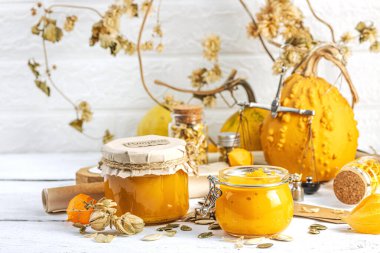 Antika eczacılık tarzında sağlıklı gıda konsepti. Ev yapımı kabak püresi ve beyaz ahşap bir masada cam kavanozlarda humus. Balkabağı, kurutulmuş zıpzıp ve bitki özü ile kırsal sonbahar natürmortu, kopyalama alanı