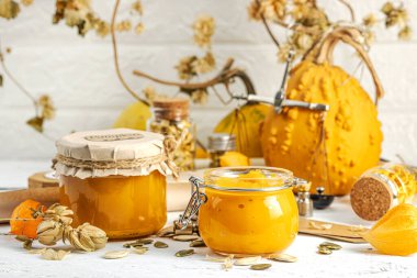 Antika eczacılık tarzında sağlıklı gıda konsepti. Ev yapımı kabak püresi ve beyaz ahşap bir masada cam kavanozlarda humus. Balkabağı, kurutulmuş zıpzıp ve bitki özü ile kırsal sonbahar natürmortu, kopyalama alanı