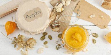 Antika eczacılık tarzında sağlıklı gıda konsepti. Ev yapımı balkabağı püresi, beyaz ahşap bir masada cam kavanozlarda humus. Balkabağı, kurutulmuş zıpzıp ve bitki salgısı ve pankart formatlı kırsal sonbahar yaşamı