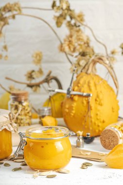 Antika eczacılık tarzında sağlıklı gıda konsepti. Ev yapımı kabak püresi ve beyaz ahşap bir masada cam kavanozlarda humus. Balkabağı, kurutulmuş zıpzıp ve bitki özü ile kırsal sonbahar natürmortu, kopyalama alanı