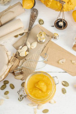 Antika eczacılık tarzında sağlıklı gıda konsepti. Ev yapımı kabak püresi ve beyaz ahşap bir masada cam kavanozlarda humus. Balkabağı, kurutulmuş zıpzıp ve bitki özü ile kırsal sonbahar natürmortu.