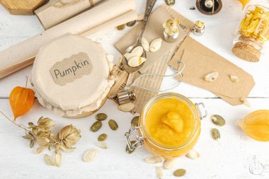 Antika eczacılık tarzında sağlıklı gıda konsepti. Ev yapımı kabak püresi ve beyaz ahşap bir masada cam kavanozlarda humus. Balkabağı, kurutulmuş zıpzıp ve bitki özü ile kırsal sonbahar natürmortu.