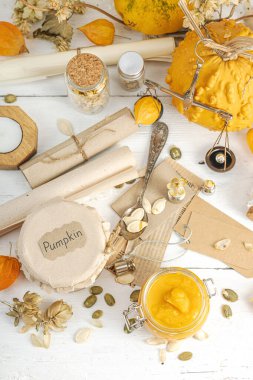 Antika eczacılık tarzında sağlıklı gıda konsepti. Ev yapımı kabak püresi ve beyaz ahşap bir masada cam kavanozlarda humus. Balkabağı, kurutulmuş zıpzıp ve bitki özü ile kırsal sonbahar natürmortu.