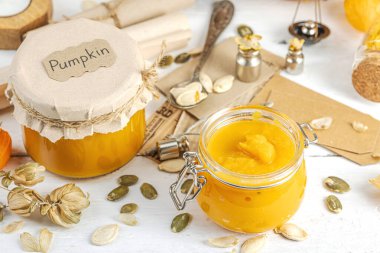 Antika eczacılık tarzında sağlıklı gıda konsepti. Ev yapımı kabak püresi ve beyaz ahşap bir masada cam kavanozlarda humus. Kabak, kurutulmuş zıpzıp ve bitki örtüsüyle dolu kırsal bir sonbahar hayatı. Kapan.