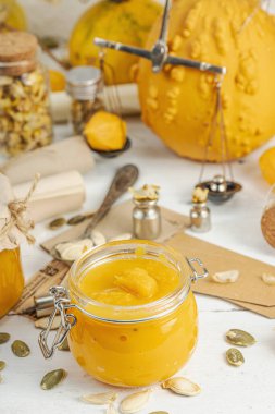 Antika eczacılık tarzında sağlıklı gıda konsepti. Ev yapımı kabak püresi ve beyaz ahşap bir masada cam kavanozlarda humus. Kabak, kurutulmuş zıpzıp ve bitki örtüsüyle dolu kırsal bir sonbahar hayatı. Kapan.