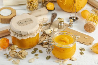 Antika eczacılık tarzında sağlıklı gıda konsepti. Ev yapımı kabak püresi ve beyaz ahşap bir masada cam kavanozlarda humus. Kabak, kurutulmuş zıpzıp ve bitki örtüsüyle dolu kırsal bir sonbahar hayatı. Kapan.