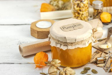 Antika eczacılık tarzında sağlıklı gıda konsepti. Ev yapımı kabak püresi ve beyaz ahşap bir masada cam kavanozlarda humus. Balkabağı, kurutulmuş zıpzıp ve bitki özü ile kırsal sonbahar natürmortu, kopyalama alanı