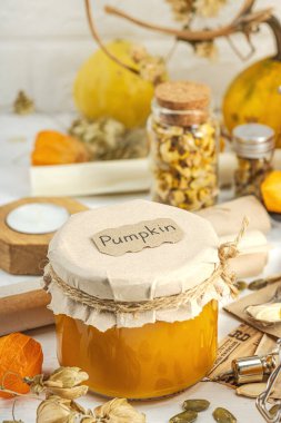 Antika eczacılık tarzında sağlıklı gıda konsepti. Ev yapımı kabak püresi ve beyaz ahşap bir masada cam kavanozlarda humus. Kabak, kurutulmuş zıpzıp ve bitki örtüsüyle dolu kırsal bir sonbahar hayatı. Kapan.