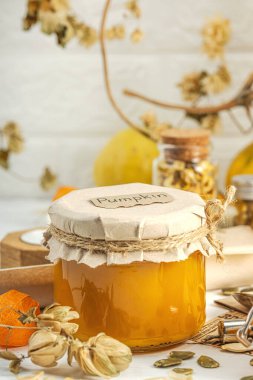 Antika eczacılık tarzında sağlıklı gıda konsepti. Ev yapımı kabak püresi ve beyaz ahşap bir masada cam kavanozlarda humus. Kabak, kurutulmuş zıpzıp ve bitki örtüsüyle dolu kırsal bir sonbahar hayatı. Kapan.