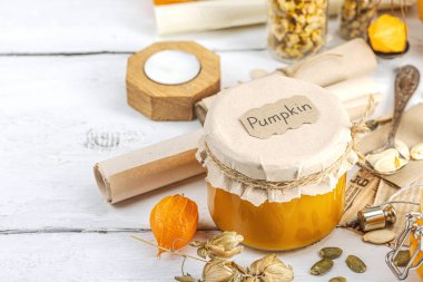 Antika eczacılık tarzında sağlıklı gıda konsepti. Ev yapımı kabak püresi ve beyaz ahşap bir masada cam kavanozlarda humus. Balkabağı, kurutulmuş zıpzıp ve bitki özü ile kırsal sonbahar natürmortu, kopyalama alanı