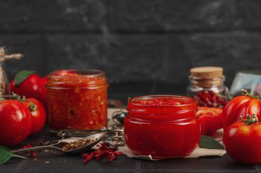 Ev yapımı domates sosu, ketçap ve koyu arka planda taze aile yadigarı domateslerle dolu cam kavanozlar. Tarif kağıdı, terazi, baharat ve mutfak bıçağı ile klasik eczacılık tarzı, kopyalama alanı