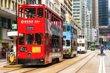 Hong Kong Adası 'ndaki modern binanın arka planına sahip ünlü çift katlı tramvayların görüntüsü.