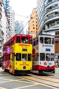 Hong Kong Adası 'ndaki modern binanın arka planına sahip ünlü çift katlı tramvayların görüntüsü.