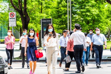 Taipei, Tayvan - 4 Mayıs 2020: Bazı yayalar kendilerini koronavirüsten (COVID-19) korumak için yüz maskesi takıyorlar Tayvan 'ın Taipeis Xinyi ilçesinde karşıdan karşıya geçiyorlar..