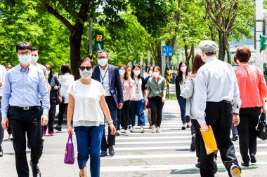 Taipei, Tayvan - 4 Mayıs 2020: Bazı yayalar kendilerini koronavirüsten (COVID-19) korumak için yüz maskesi takıyorlar Tayvan 'ın Taipeis Xinyi ilçesinde karşıdan karşıya geçiyorlar..