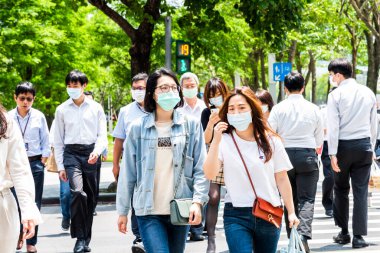 Taipei, Tayvan - 4 Mayıs 2020: Bazı yayalar kendilerini koronavirüsten (COVID-19) korumak için yüz maskesi takıyorlar Tayvan 'ın Taipeis Xinyi ilçesinde karşıdan karşıya geçiyorlar..