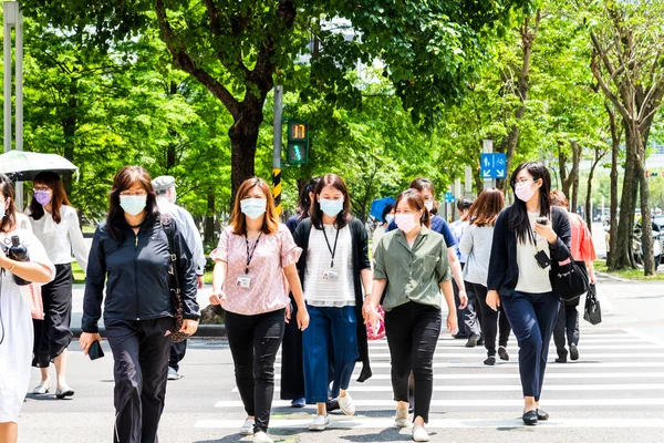 Taipei, Tayvan - 4 Mayıs 2020: Bazı yayalar kendilerini koronavirüsten (COVID-19) korumak için yüz maskesi takıyorlar Tayvan 'ın Taipeis Xinyi ilçesinde karşıdan karşıya geçiyorlar..