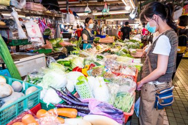 Kadın müşteriler Kuzey Kaohsiung, Tayvan 'daki büyük bir geleneksel pazardan sebze seçiyorlar..
