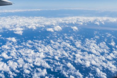 Uçuş sırasında mavi gökyüzü ve beyaz bulutların görüntüsü.