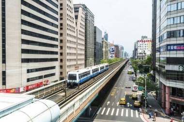 Wenhu ya da Taipei MRT 'nin Tayvan' daki Brown hattı. Tren, açık mavi gökyüzünün altındaki binalar arasında Taipei Metro Sistemi 'nin yüksek raylarında ilerliyor..