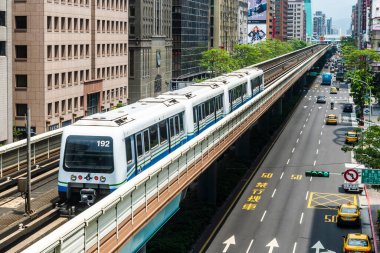 Wenhu ya da Taipei MRT 'nin Tayvan' daki Brown hattı. Tren, açık mavi gökyüzünün altındaki binalar arasında Taipei Metro Sistemi 'nin yüksek raylarında ilerliyor..