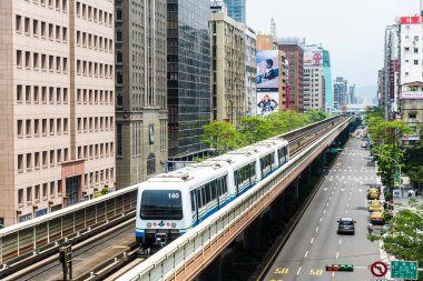 Tayvan 'daki Taipei Metro' nun Wenhu veya Brown hattı. Mavi gökyüzünün altındaki ofis kuleleri arasında Taipei Metro Sistemi 'nin yüksek raylarında giden bir trenin görüntüsü.