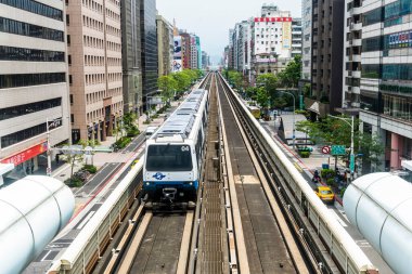 Wenhu ya da Taipei MRT 'nin Tayvan' daki Brown hattı. Tren, açık mavi gökyüzünün altındaki binalar arasında Taipei Metro Sistemi 'nin yüksek raylarında ilerliyor..