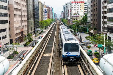 Tayvan 'daki Taipei Metro' nun Wenhu veya Brown hattı. Mavi gökyüzünün altındaki ofis kuleleri arasında Taipei Metro Sistemi 'nin yüksek raylarında giden bir trenin görüntüsü.
