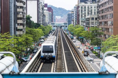 Wenhu ya da Taipei MRT 'nin Tayvan' daki Brown hattı. Tren, açık mavi gökyüzünün altındaki binalar arasında Taipei Metro Sistemi 'nin yüksek raylarında ilerliyor..