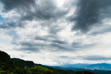 Dağın tepesinde fırtınalı bulutlarla dramatik bir gökyüzü.
