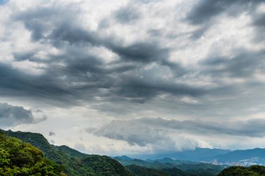 Dağın tepesinde fırtınalı bulutlarla dramatik bir gökyüzü.