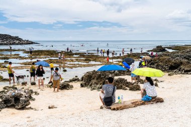 Turistler Pingtung, Tayvan 'daki Kenting Ulusal Parkı kıyısındaki gelgit bölgesini keşfediyorlar.