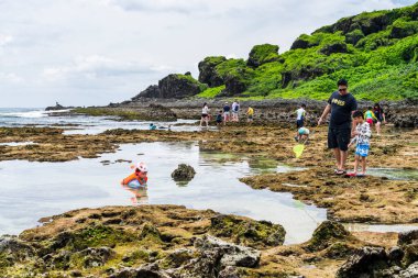Turistler Pingtung, Tayvan 'daki Kenting Ulusal Parkı kıyısındaki gelgit bölgesini keşfediyorlar.