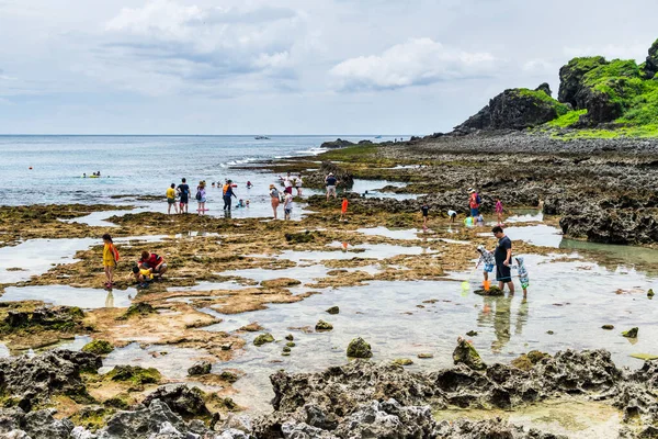 Turistler Pingtung, Tayvan 'daki Kenting Ulusal Parkı kıyısındaki gelgit bölgesini keşfediyorlar.