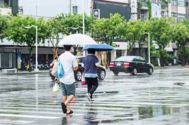 Yağmur mevsiminde, yayalar Kaohsiung City, Tayvan 'da karşıdan karşıya geçiyorlar..