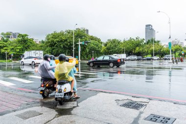 Yağmur mevsiminde, motosiklet sürücüleri Kaohsiung City, Tayvan caddesinde trafik ışığını bekliyorlar..