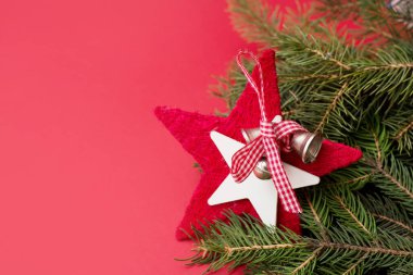 Kırmızı zili ve kırmızı kurdeleyle süslenmiş kırmızı bir yıldız kırmızı arka planda bir noel ağacı dalında fotokopi alanı ile