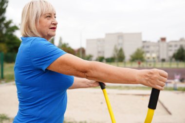 64 yaşında, dışarıda egzersiz yapan güzel, sağlıklı bir kadın.
