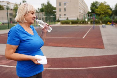 Sportif olgun kadınlar egzersizden sonra şişeyi açık havada su ile tutarlar. sağlıklı yaşam tarzı kavramı