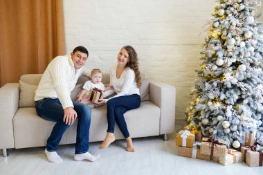 Mutlu aile kanepede oturuyor ve Noel ağacının yakınındaki dekore edilmiş yeni yılı kutluyor. Noel 'i kutlamak.