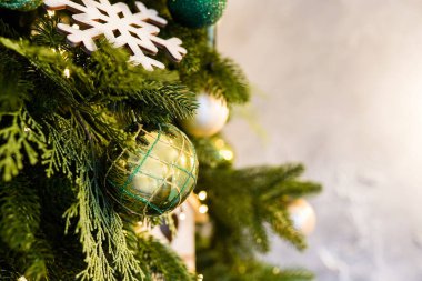 Noel ağacında parıldayan yeşil ve altın oyuncaklar. Parlak bir Noel oyuncağı Odadaki ışıldayan yeni yıl ağacında.