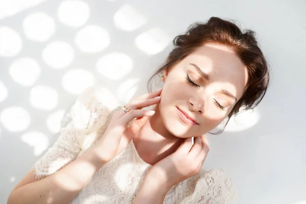 Close up portrait of woman with closed eyes enjoying sunlights on white background