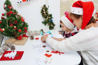 Noel 'de aile birlikte tebrik kartı hazırlıyor. Torunuyla büyükannesi evde.