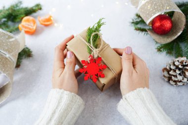 Noel hediyesi kutusuyla kış süsleri taşıyan bir kadının elleri