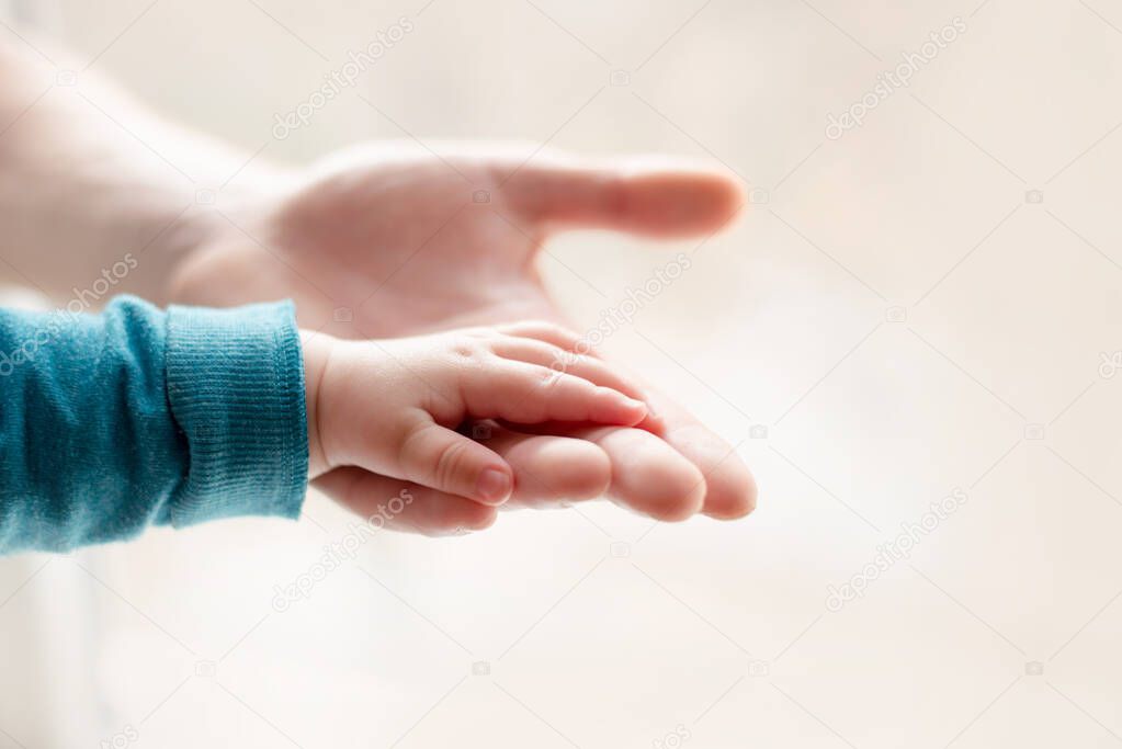a parent father holds the hand of a small child.