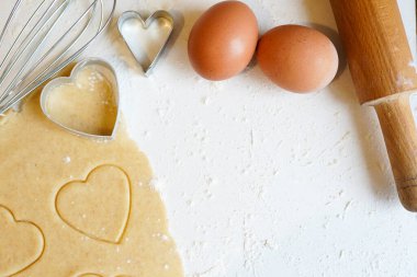 Sevgililer Günü için pişirme konsepti. Kalp şeklinde kesiciler ve beyaz ahşap masa üzerinde, kopyalanmış yumurtalar.