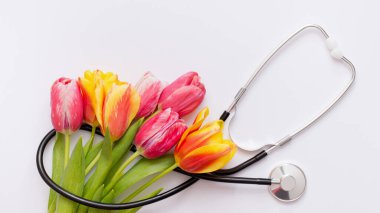 Beyaz arka planda pembe laleler ve steteskop. Ulusal Doktor Günü. Mutlu hemşire günleri..