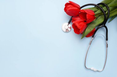 Mavi arka planda steteskoplu bir sürü kırmızı lale. Ulusal Doktor Günü. Hemşire günün kutlu olsun. Kopyalama alanı olan üst görünüm.