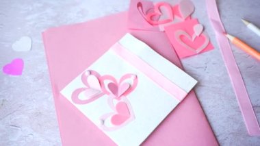 Beyaz ahşap arka planda pembe kalpleri olan el yapımı bir kart. Sevgililer günü aşkı